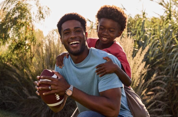 father and son playing baseball in a field. The dad is wearing a Citizen stylish watch.